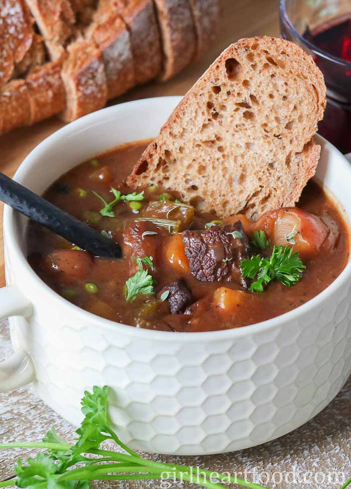 Close-up of a bowl of moose stew with a slice of bread and spoon dunked into it.