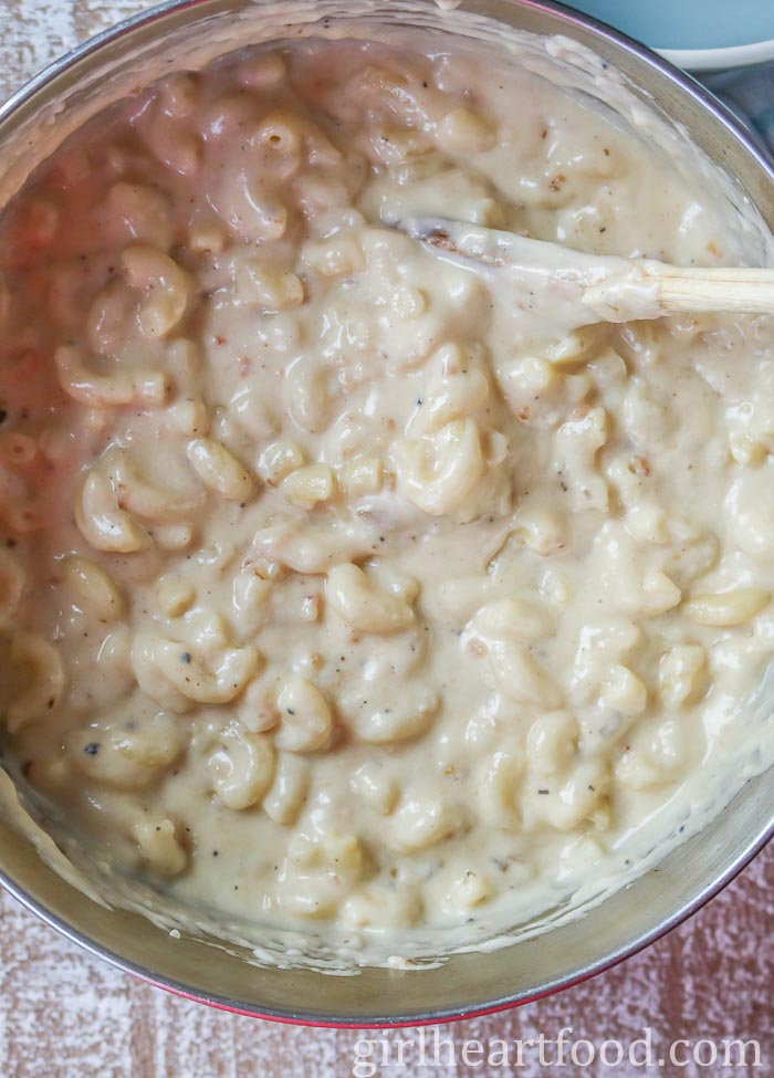 Pot of creamy mac and cheese being stirred with a wooden spoon.