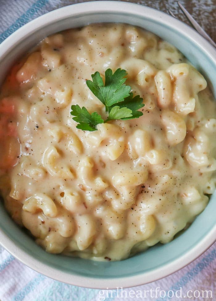 Close-up of a bowl of creamy macaroni and cheese garnished with parsley.