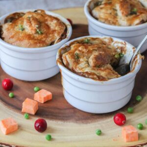 Three individual dishes of chicken pot pie with a spoon dunked in one of them.