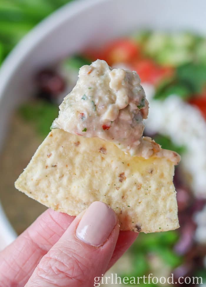 Hand holding a chip that has been dipped in bean dip.