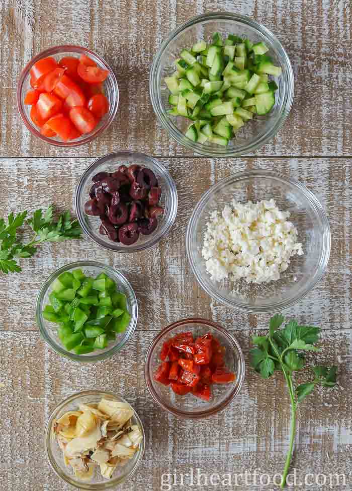 Dishes of garnish for Mediterranean white bean dip.