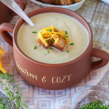 Bowl of creamy cauliflower leek soup garnished with croutons, chives and cheddar.