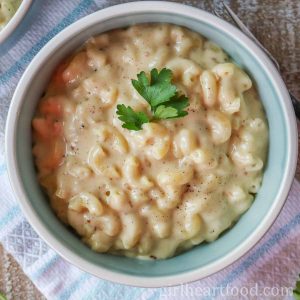 Bowl of creamy macaroni and cheese garnished with fresh parsley.