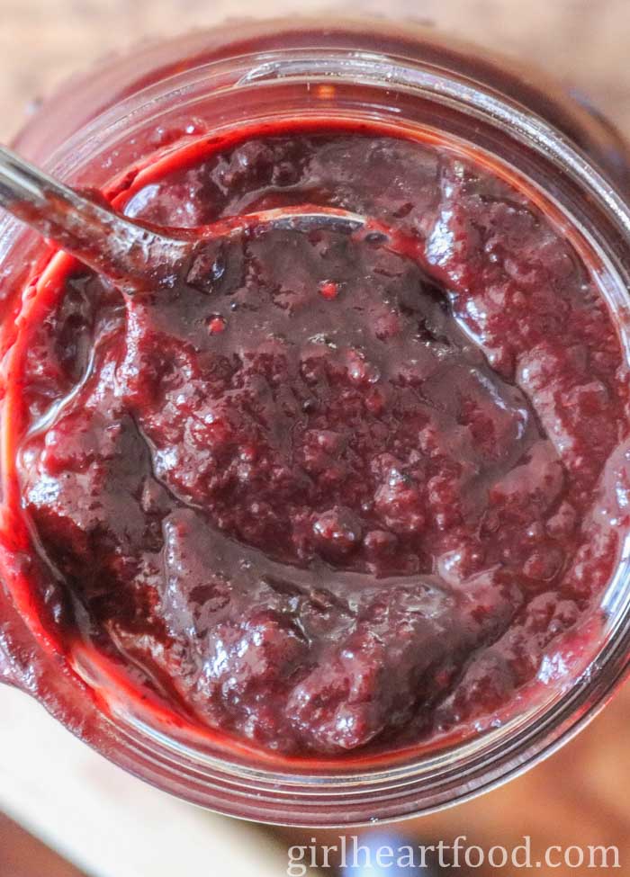 Overhead shot of a jar of blueberry BBQ sauce with a spoon in the jar.