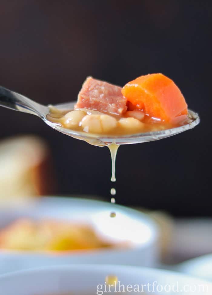 Spoonful of Newfoundland boiled beans with broth dripping off the spoon.