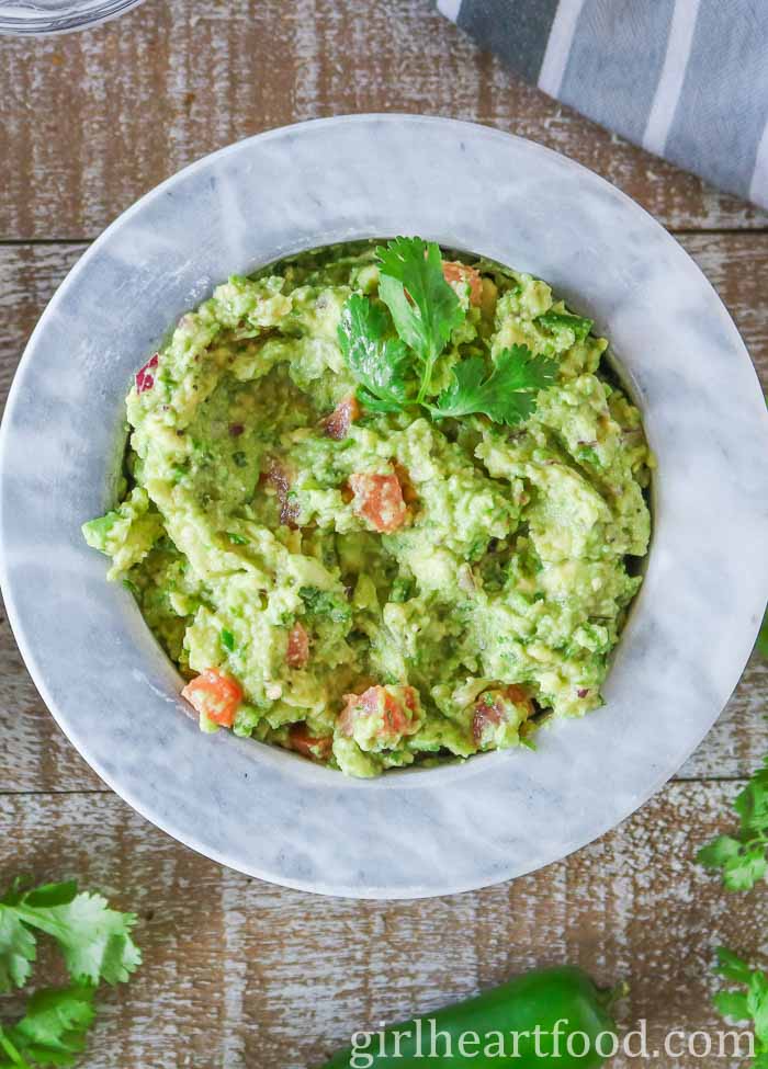Bowl of guacamole garnished with cilantro.