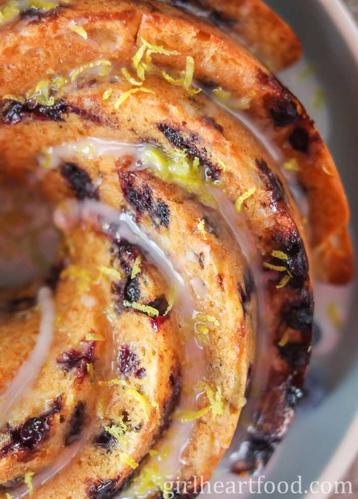 Close-up of a glazed blueberry cake with lemon zest over top.