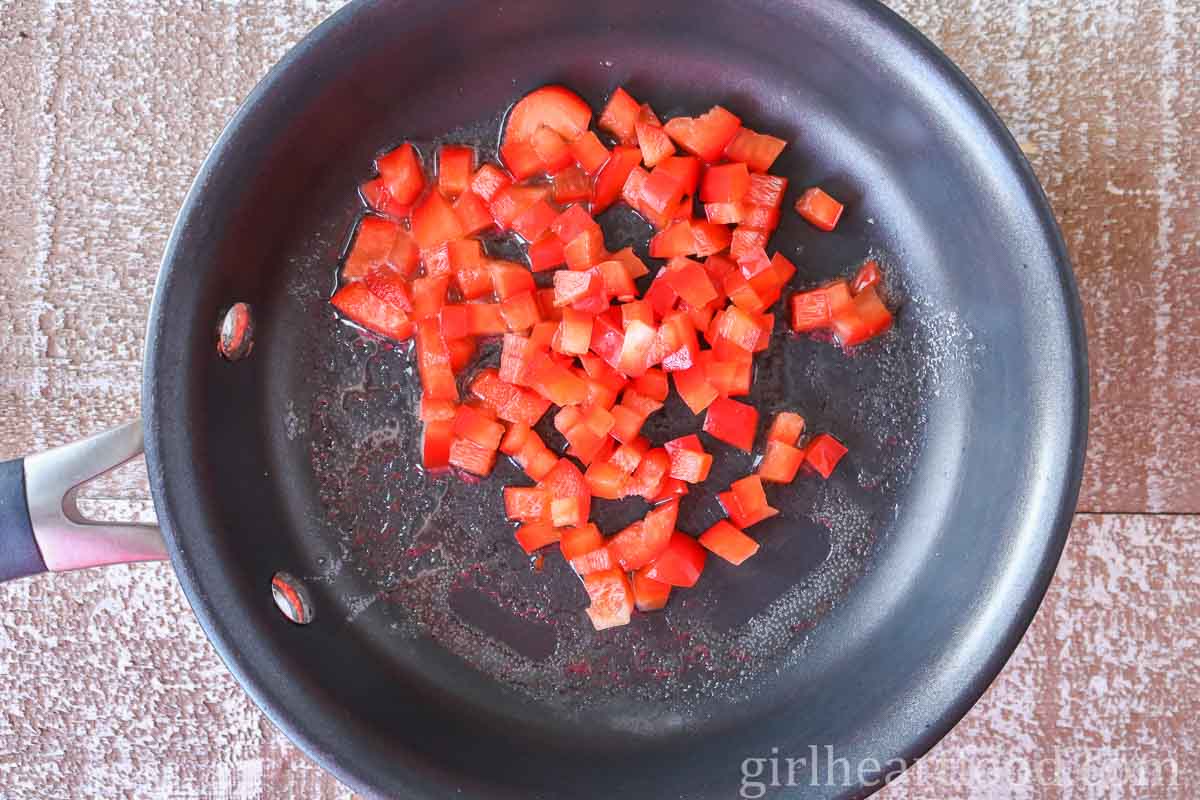 Diced red bell pepper cooking in a non-stick fry pan.