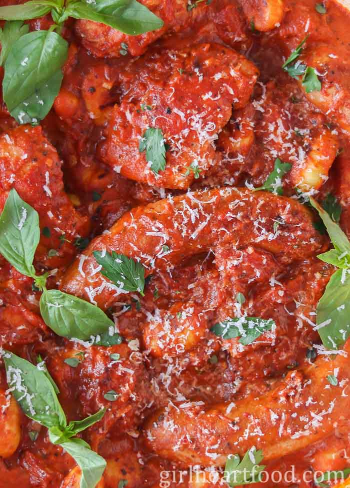 Close-up of chicken, sausage and gnocchi in tomato sauce.