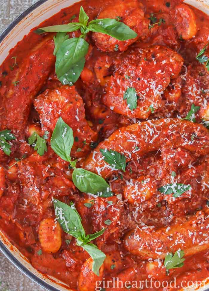 Close-up of a pan of chicken, sausage & gnocchi in tomato sauce.