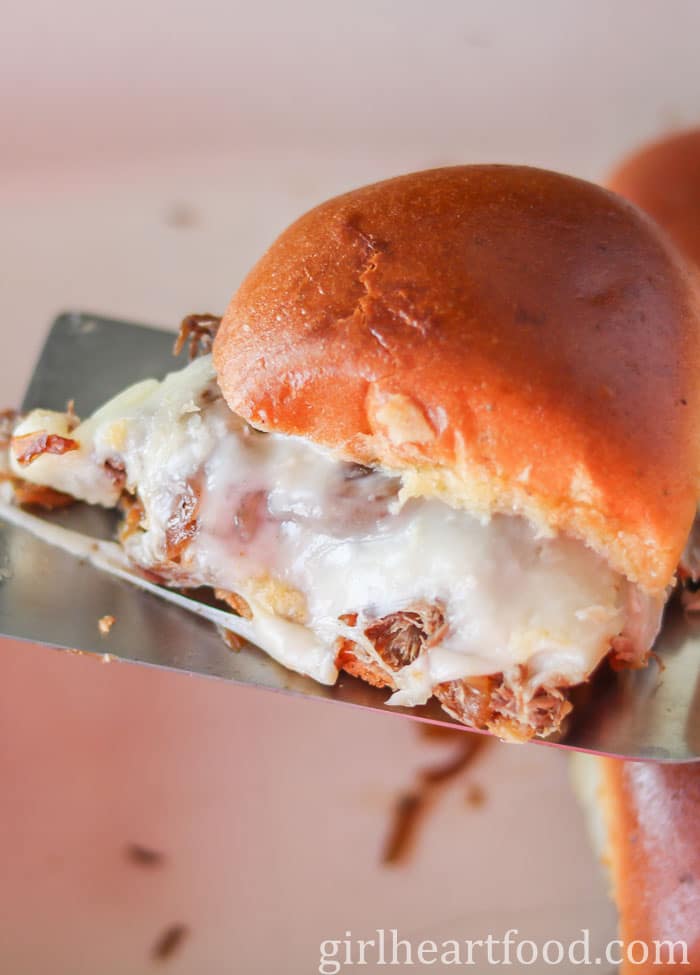 Cheesy slider on top of a spatula.