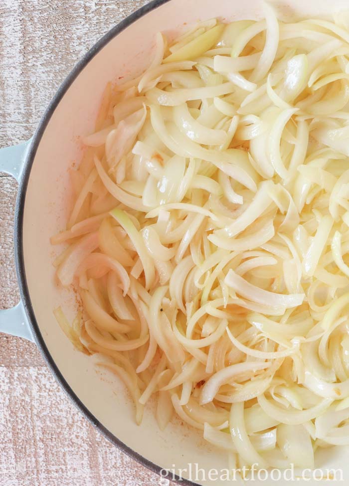 Sliced onions in a pan that are just slightly cooked.