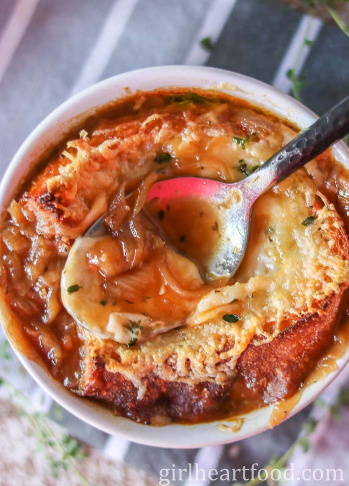 Bowl of French onion soup with a spoonful of soup resting on top.
