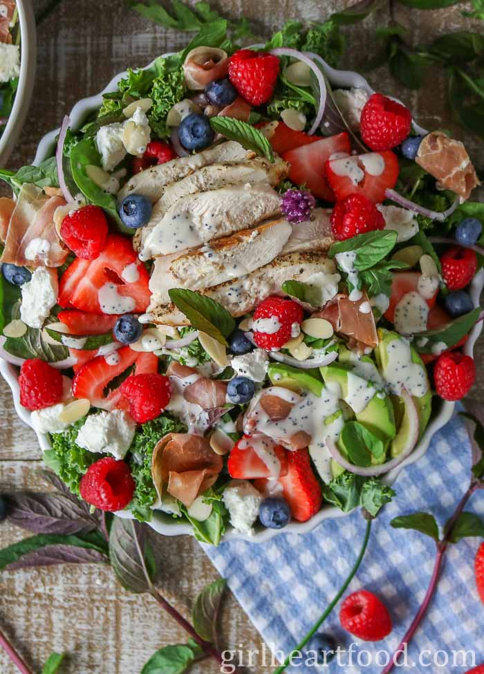 Bowl of green salad with poppy seed dressing drizzled over top.