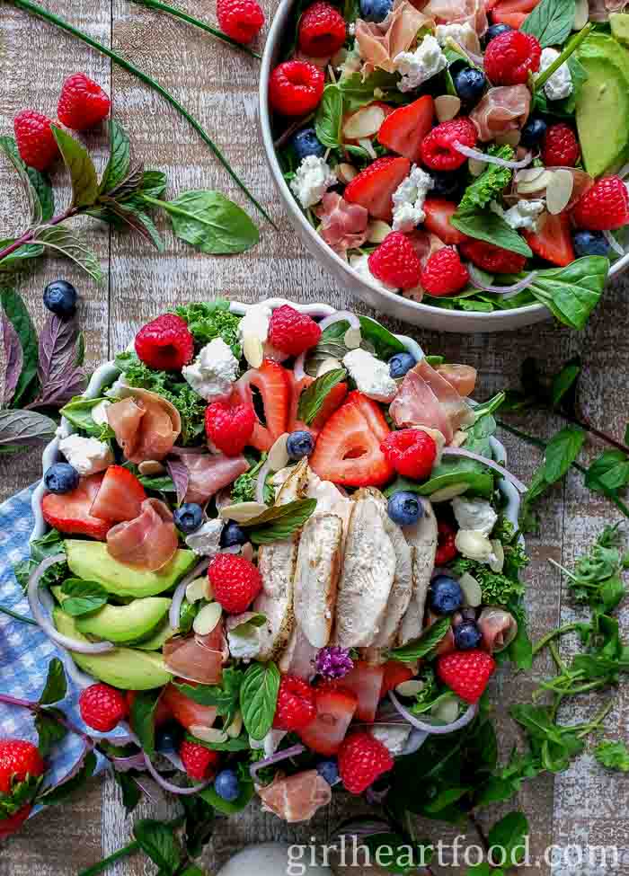 Two bowls of green salad before the dressing is drizzled over top.