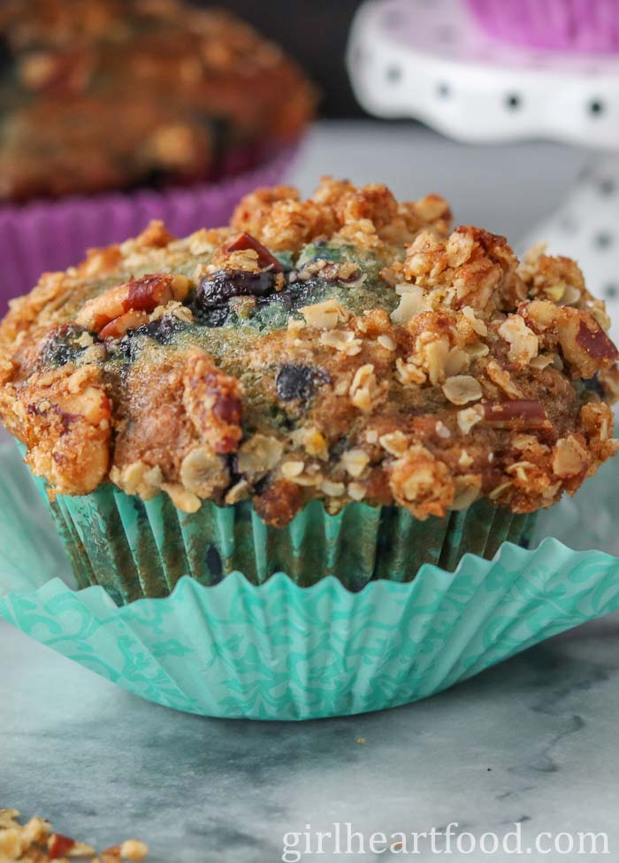 Close-up of a blueberry muffin wrapped in a teal muffin liner.