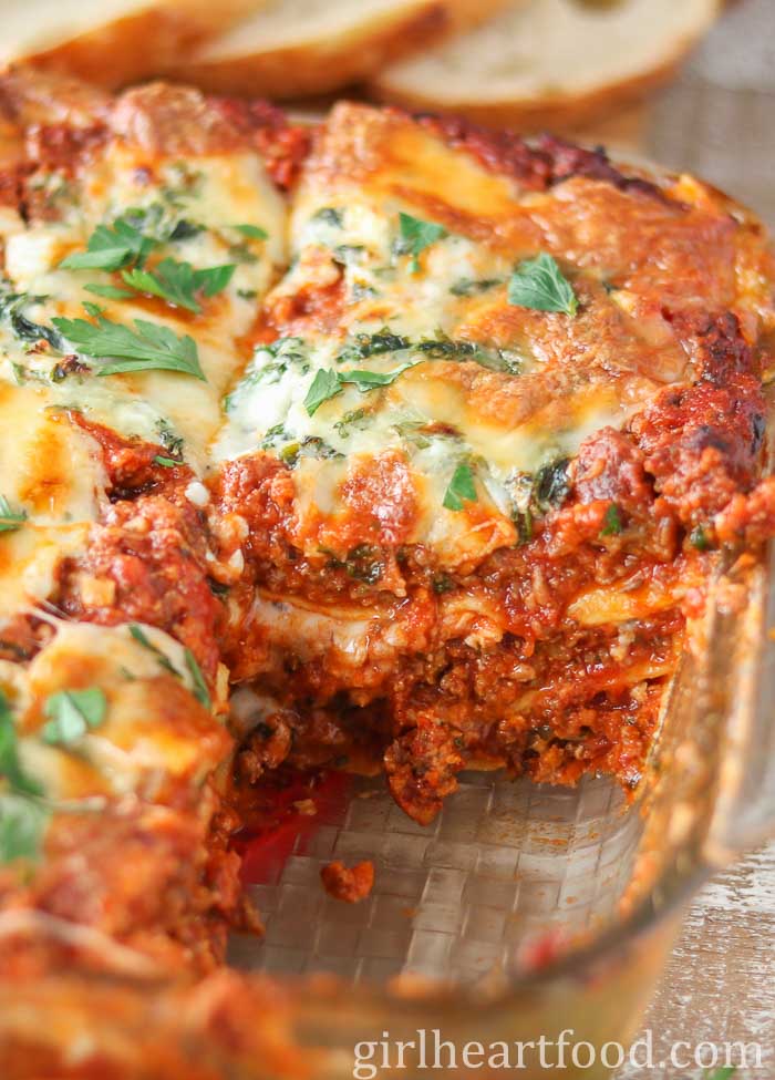 Meat lasagna in a baking dish with one piece taken out.