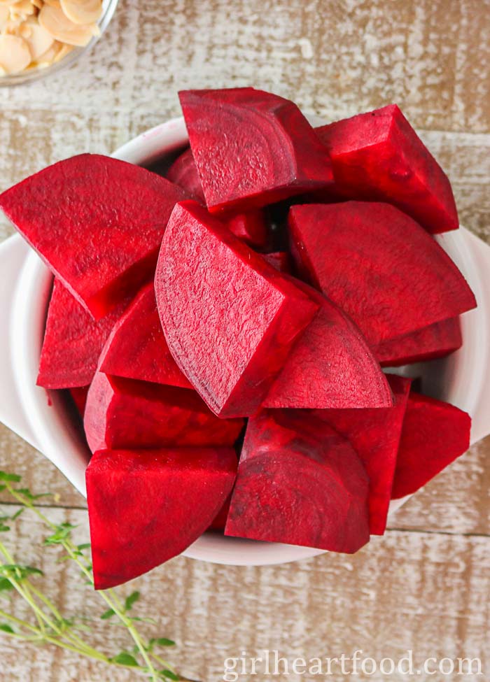 Chunks of peeled fresh beets in a white dish.