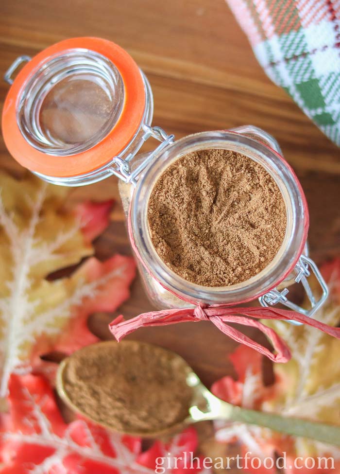 Glass jar of homemade pumpkin spice alongside a spoonful of pumpkin spice.