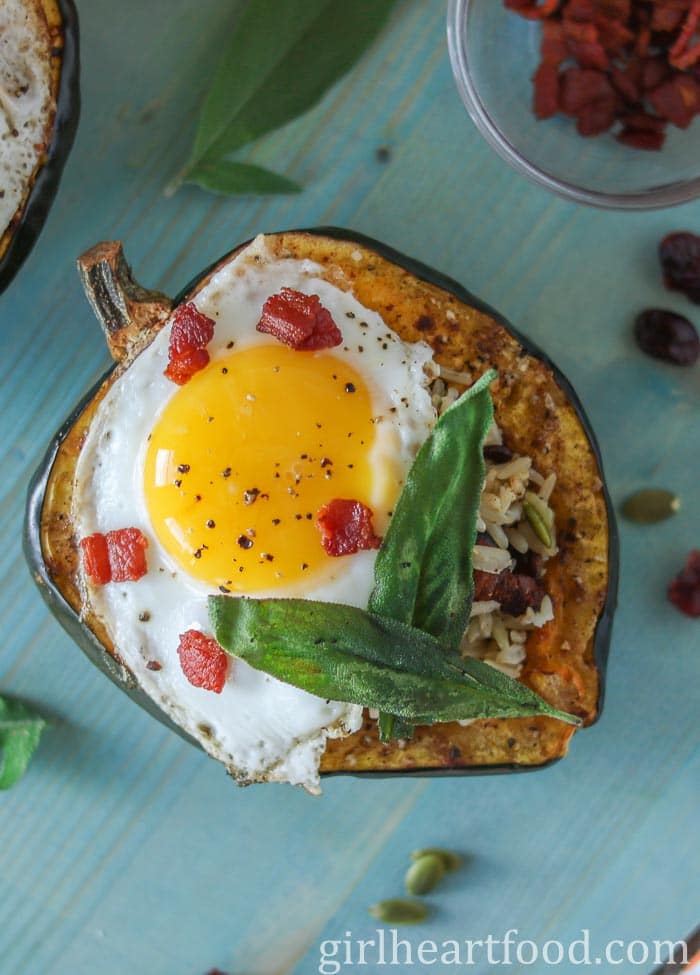 Roasted stuffed acorn squash topped with a fried egg, crispy bacon and sage leaves. 