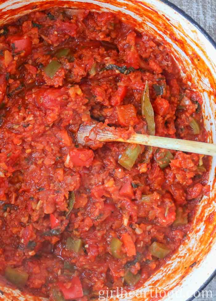 Vegetable tomato red sauce in a pot with a wooden spoon.