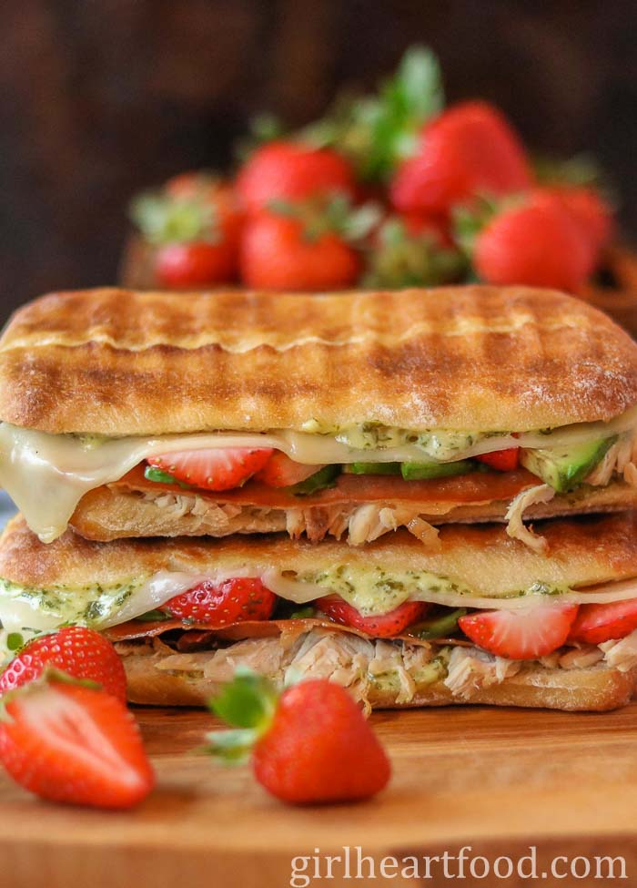Stack of two turkey panini sandwiches next to strawberries.