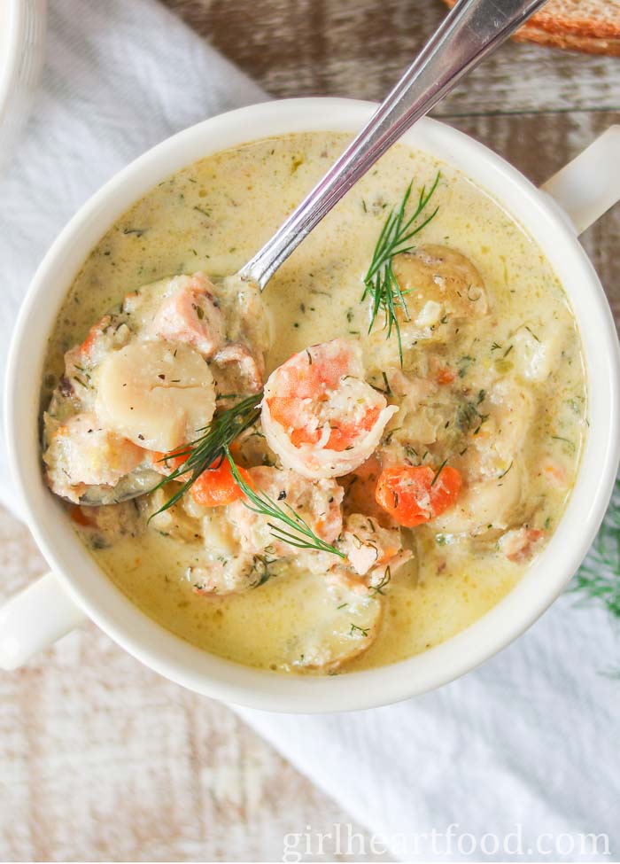 Bowl of creamy seafood chowder with a spoonful of the chowder resting on top.