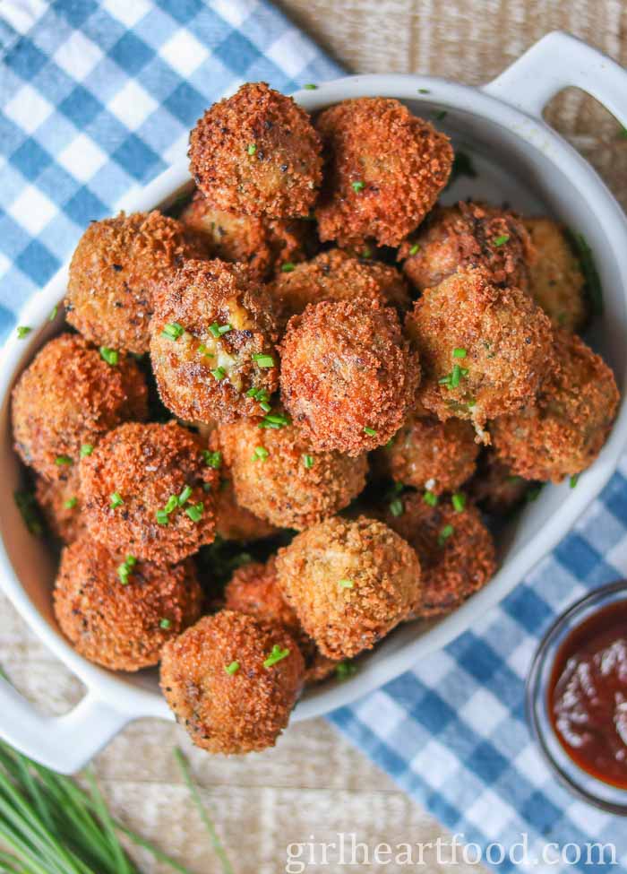 Fried mashed potato balls in a dish garnished with chives.