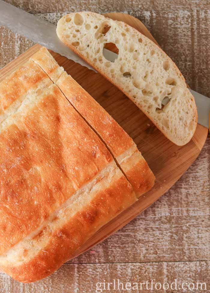 Loaf of bread with a slice cut off by a knife.