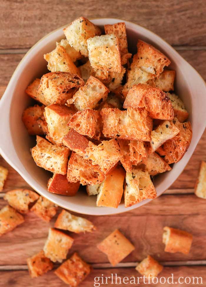 Homemade croutons in a bowl with some spilling out.