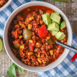 Overhead shot of a bowl of lentil chili topped with diced avocado.