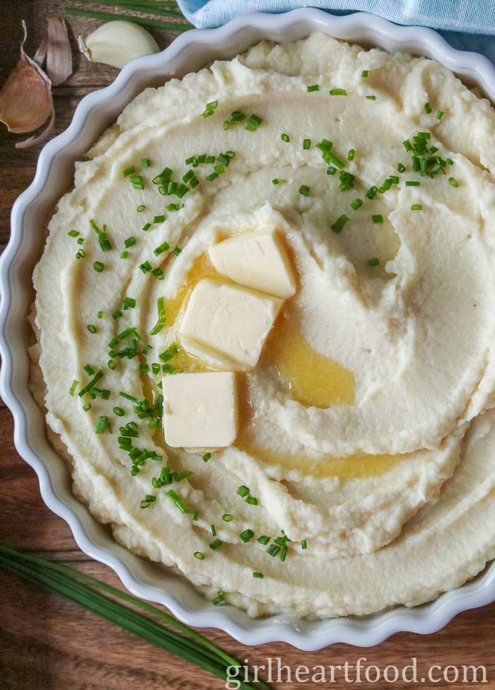 Celeriac puree in a dish topped with chives and butter.