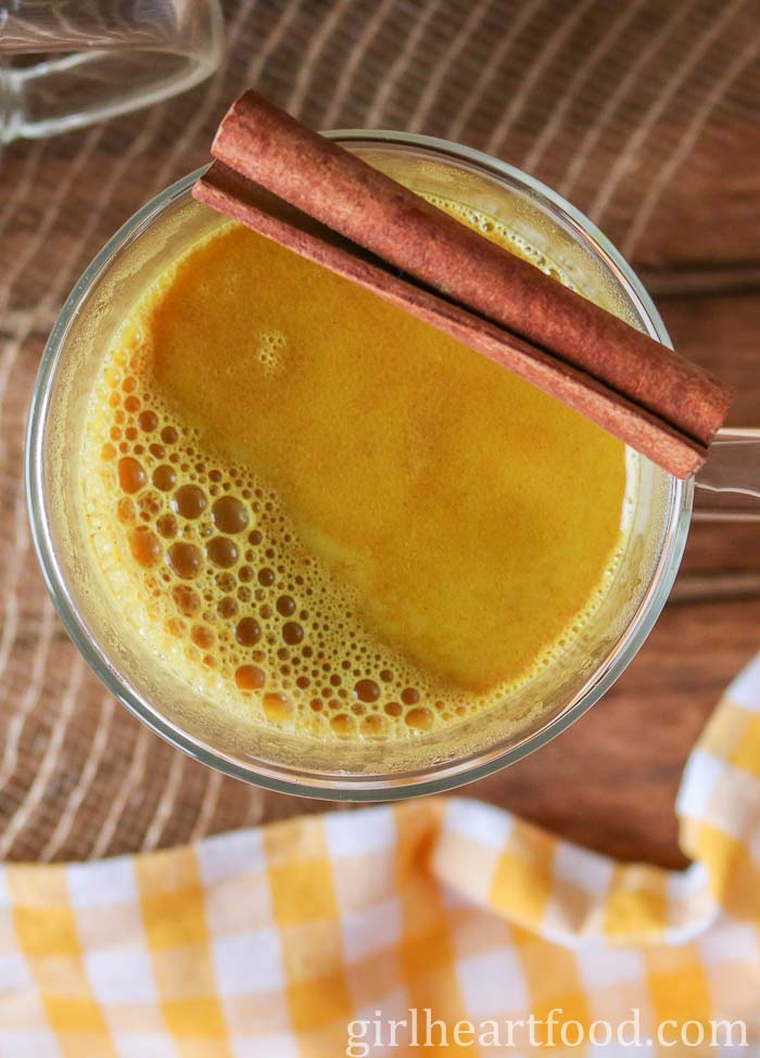 Mug of golden milk with a cinnamon stick resting over top.