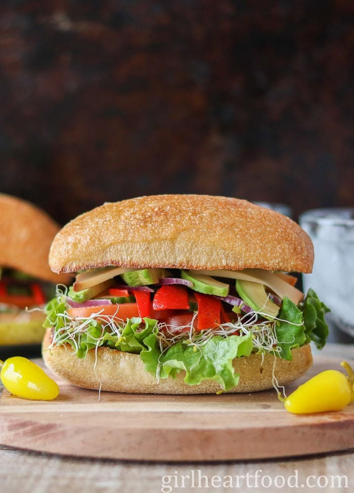 A veggie sandwich with pickled hot peppers on either side of it.