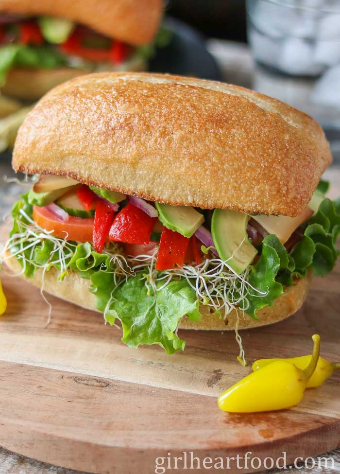 A veggie sandwich next to pickled hot peppers.