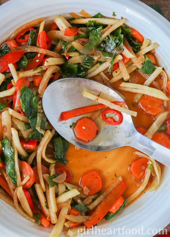 Large serving spoon resting in a bowl of vegetable stir-fry.