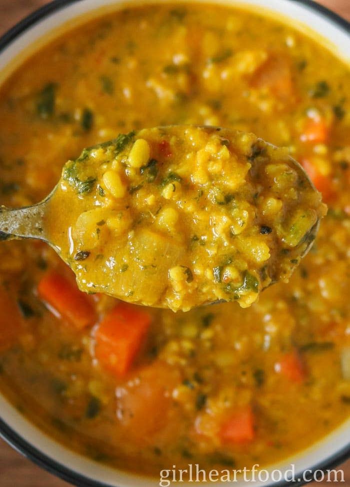 Close-up of a spoonful of moong bean soup from a bowl.