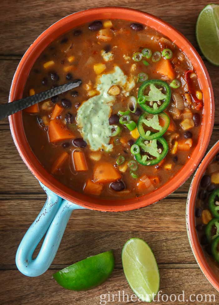 Bowl of black bean sweet potato soup garnished with jalapeno and crema.