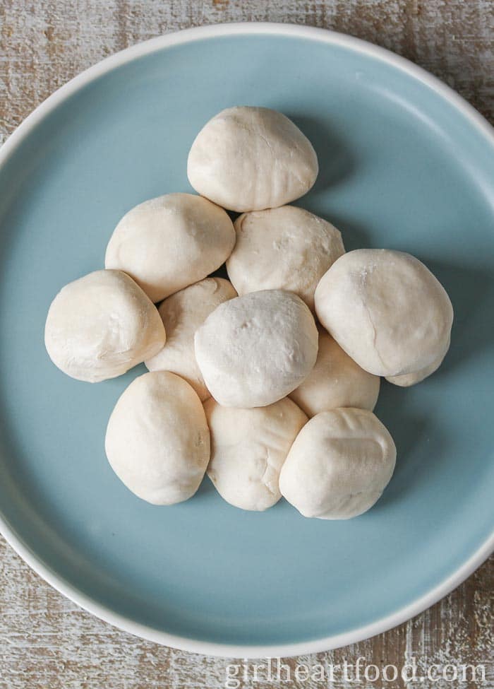 Touton dough rolled into little balls on a blue plate.