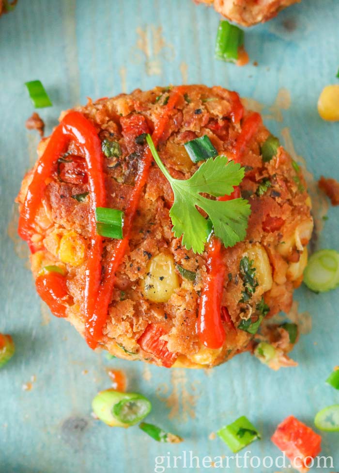 Pinto bean fritter drizzled with hot sauce and topped with green onion and cilantro.