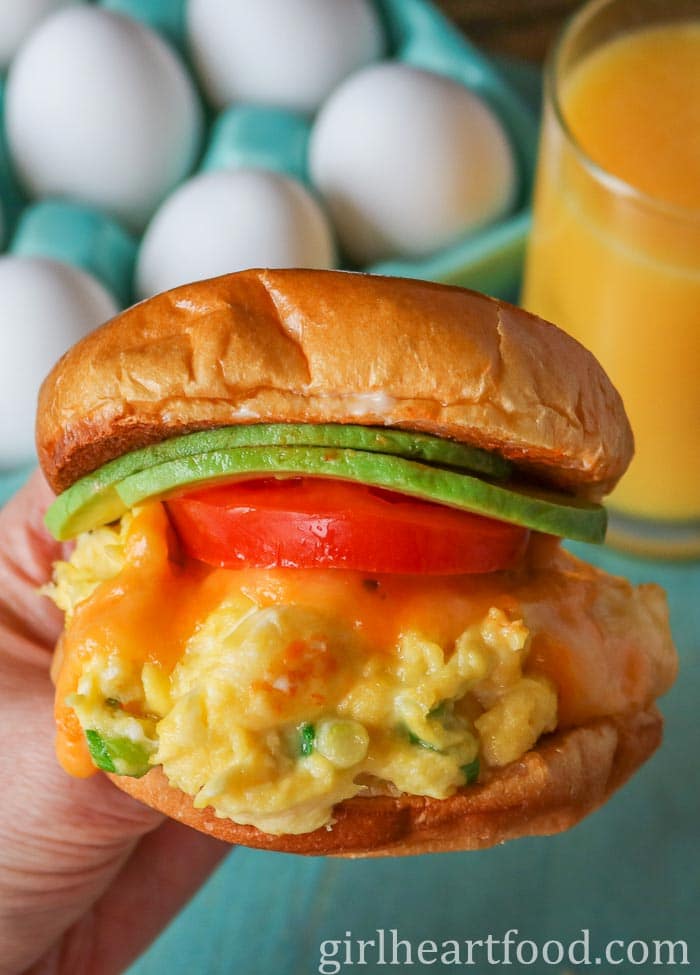 Hand holding a cheesy egg sandwich.