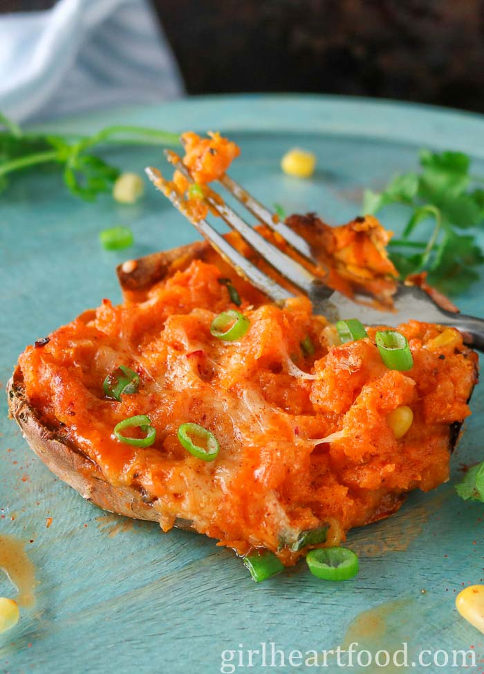 A fork resting on a stuffed baked sweet potato.