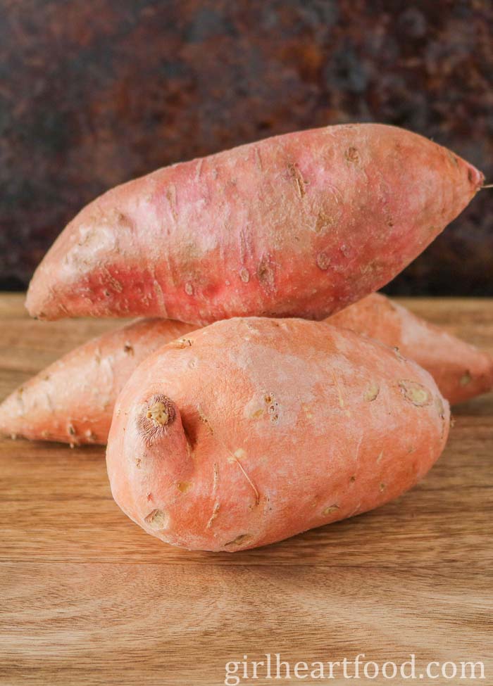 Three uncooked and unpeeled sweet potatoes.