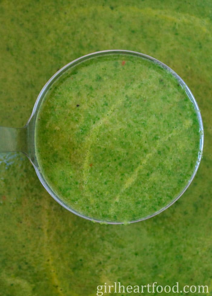 Close-up of a ladle of green vegetable soup.