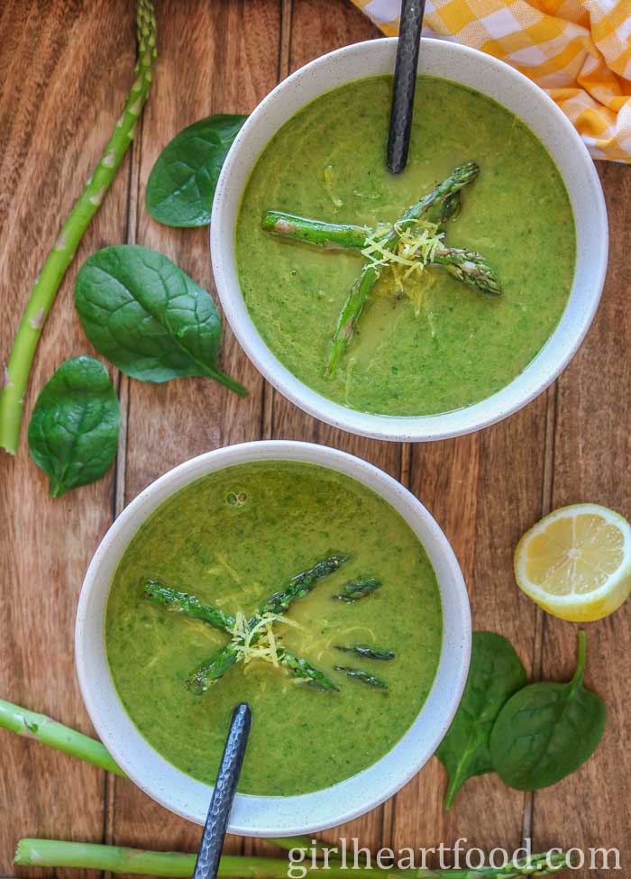 Two bowls of asparagus spinach soup garnished with asparagus and lemon zest.