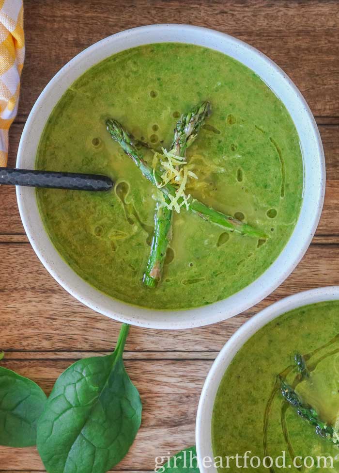 Bowl of asparagus spinach soup garnished with asparagus and lemon zest.