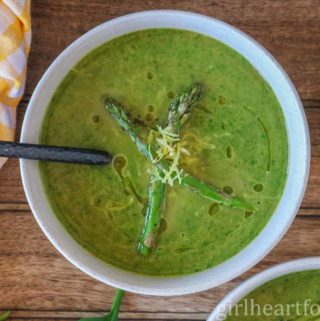 Bowl of asparagus spinach soup garnished with asparagus and lemon zest.