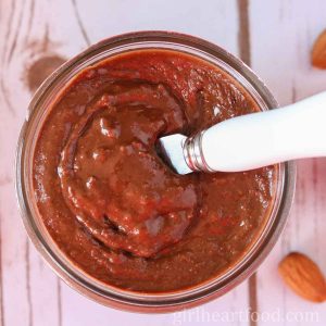 Jar of chocolate almond butter with a spreader dipped into it.