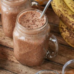 Glass of chocolate peanut butter smoothie next to bananas.